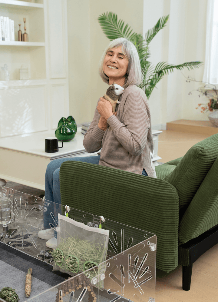 Guinea Colony Starter Kit - Critter Colony Club - elder woman in living room with guinea pig and Guinea Colony guinea pig cage